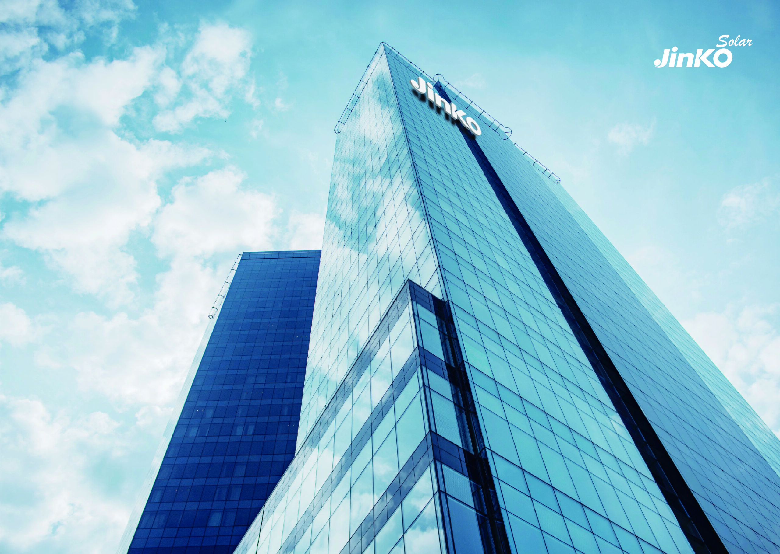 The Jinko Solar logo on the front of a glass skyscraper in a cloudy sky.